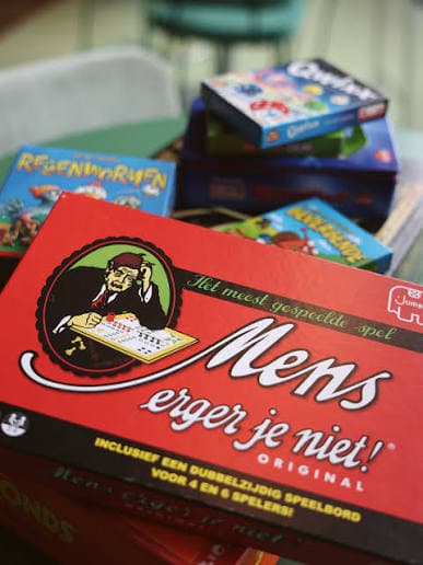 Stapel gezelschapsspellen op tafel, met Mens erger je niet, Regenwormen en Qwixx