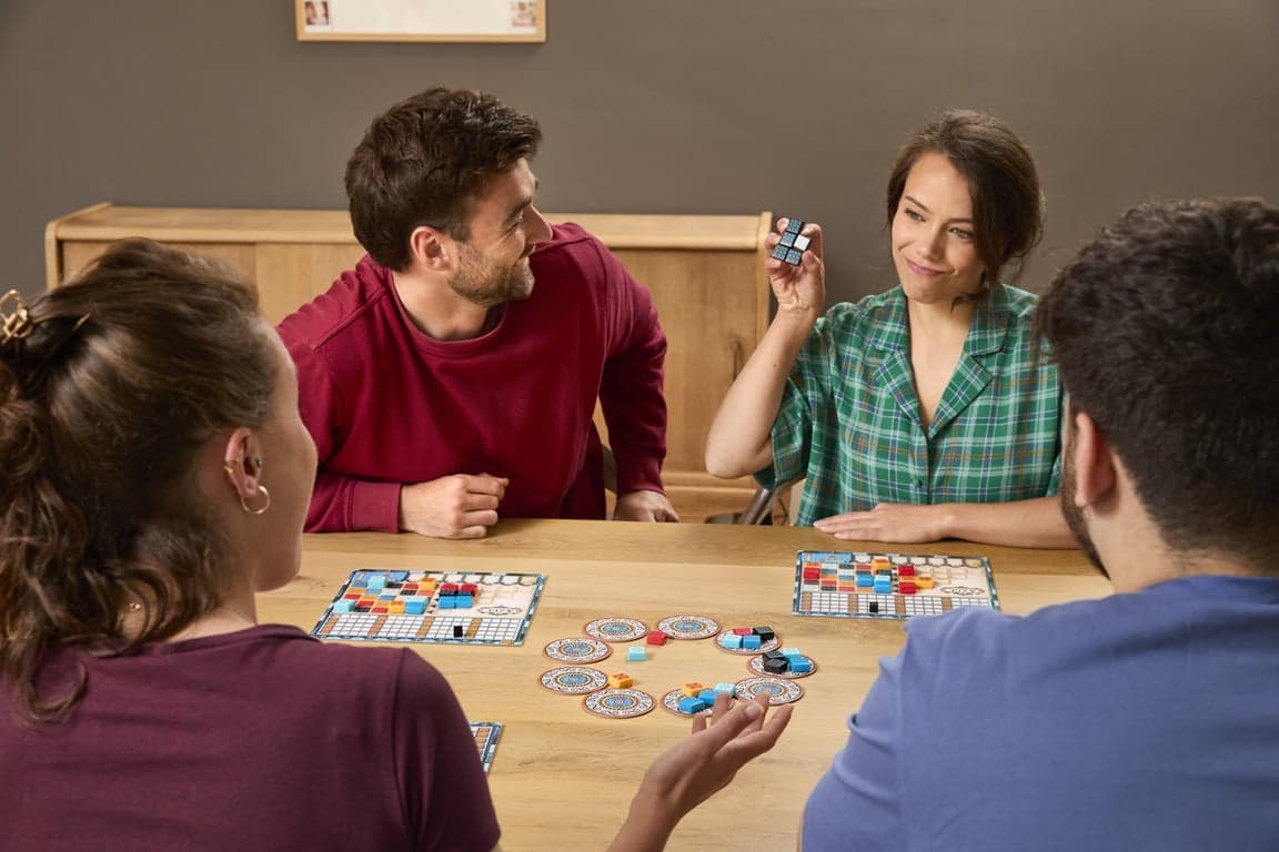 Vier volwassenen aan tafel met het bordspel Azul
